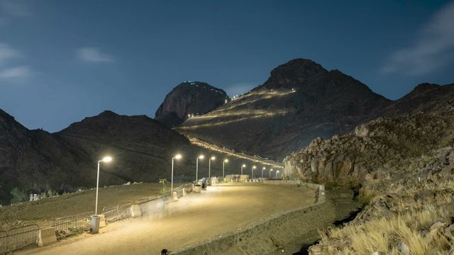 The illuminated path zig-zagging up Jabal al-Nur in Makkah at night, under a moving sky.