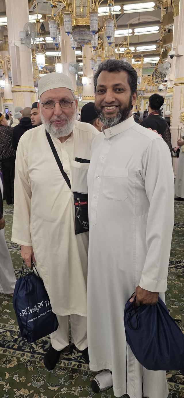 Two Amity travelers standing inside Masjid an-Nabawi beneath its gilded columns and lights
