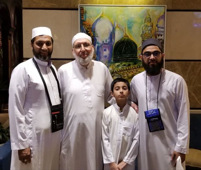 Four Amity travelers, including a boy, in a hotel lobby beneath a painting of the green dome