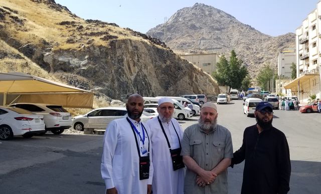 Four Amity travelers on a Makkah street with Jabal al-Nour rising behind